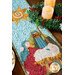 A close up on one side of the table runner, focusing on the applique Nativity scene of Jesus, Mary, and Joseph. Coordinating decor peeks into frame.