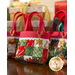 Three tiny patchwork tote bags with red straps and decorative golden charms, displayed on a table and staged with Christmas presents.