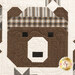 A close up on one of the patchwork bears, showing fabric, piecing, and top quilting details.