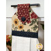 Decorative kitchen towel hanging from a drawer handle, featuring floral patterns in cream red and blue