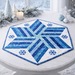 A hexagonal blue and white quilted table mat with a snowflake design on a white table.