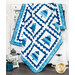 A blue and white quilt with tree patterns draped over a table, surrounded by winter decor.