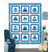 A blue and white quilt featuring twelve tree blocks framed with a stamp border, displayed on a wall near cozy furniture and decor.