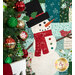 Close-up of the quilted snowman on a patchwork quilt beside a decorated Christmas tree. 