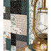 A patchwork quilt with various patterns in shades of blue, gray, and cream beside a vintage lantern.