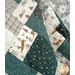 A close-up of a patchwork quilt featuring animal and nature patterns in soft muted colors.