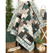 A draped patchwork quilt in muted colors surrounded by greenery and decorative items.