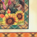 Fabric featuring turkeys and sunflowers, framed with a plaid pattern in earthy tones.