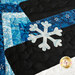 A super close up on the applique snowflake of the snowman's hat and log cabin block, demonstrating fabric, applique, piecing, top quilting, and stitching details.