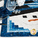 An angled shot of the snowman runner on a table set with plates, tableware, fabric napkins, wine glasses, and winter decor, demonstrating usage.