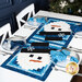 An angled shot of the snowman runner on a table set with plates, tableware, fabric napkins, wine glasses, and winter decor, demonstrating usage.