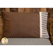 A shot of the Magic Pillowcase in brown, staged on a bed with a matching blanket in a cabin setting.