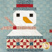 Close-up of a quilted snowman with a red hat, plaid scarf, and geometric patchwork design