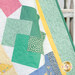 A close up on the right edge of the quilt as it's draped over a white shelf, demonstrating form, fabric, top stitching, borders, and binding details.