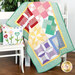 A shot of the quilt draped over a rustic white shelf and staged with the coordinating bonus pillow.