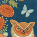 A fabric with an illustration featuring an owl, orange flowers, and a blue butterfly on a dark background.