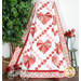 A draped quilt featuring large red, white and pink valentine hearts arranged in an Irish chain grid against a white background with floral borders.