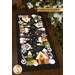 The completed Snowman Lane Flannel Table Runner, colored in vibrant Woolies Flannels, staged on a dark wooden table. A snowy tree peeks into frame and a golden banner at the top reads Laser Cut Flannel.