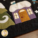 A close up on the purple house with a gold door and red button doorknob, showing details on the applique, top stitching, and embroidery.