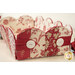 Fabric basket with a scalloped edge, featuring red and cream floral patterns and two white buttons.