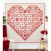 A large heart-shaped quilt in red and cream patterns hangs on a white wall, surrounded by flowers.