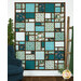 The completed Views Quilt, colored in icy teal, aqua, green, white, and brown flannel fabrics from the Woodland Woolies collection, hung on a white paneled wall and staged with coordinating decor like a pine tree, rustic wood ladder, and comfy blue chair.