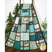 The completed Views Quilt, artfully draped from a rustic quilting ladder and staged with coordinating pine tree decor.