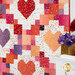 An angled shot of the quilt, showing piecing and fabric details; coordinating flowers peek into frame from the right side.