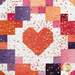 A close up on a peach pink patchwork heart block, showing piecing, layout, fabric, and top quilting details as the gold metallic heart accents leap off the colorful fabrics. 