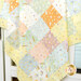 A colorful patchwork quilt featuring various pastel patterns, including polka dots and whimsical designs.