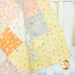 A colorful patchwork quilt with patterns of dots and cartoon animals, draped over a crib.