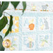 A patchwork quilt featuring whimsical animal and plant designs in pastel colors, partially obscured by green leaves.