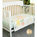 A white crib with a pastel-colored quilt featuring geometric patterns and playful designs.