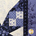 Close-up of a quilt featuring various blue and white floral patterns and top quilting details. 