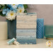 A stack of the fabrics included in the Sewing Bird FQ set with candles and a jar and glass and flowers and thread.