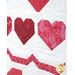 Close-up of a quilt featuring various red and pink heart patterns on a white background.