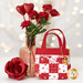 One of the Valentine's themed Tiny Tote Bags, staged with red roses and a vase with flowers and red sparkling hearts. Lights sparkle in the white background.