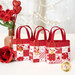 Three of the Tiny Tote Bags, lined up and staged with roses and a sparkling winter tree.