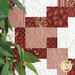 Up close of patchwork quilt featuring various shades of red patterned squares 