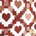 Patchwork quilt featuring a repeating pattern of hearts in shades of red and pink, set against a white background.