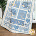 A blue and cream children's quilt featuring bunnies, hearts, and loving phrases draped over a crib