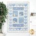 A blue children's quilt featuring bunnies and hearts hangs on a wall next to a tree and coordinating decor. 