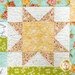 A colorful quilt featuring a large yellow star surrounded by floral and patterned fabric pieces.