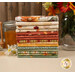 A stack of the fabrics featured in the Harvest Blooms FQ set, with flowers and jars and honey and a honey wand and wheat stalks and thread.