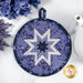 A top down shot of the round folded star hot pad on a white marble countertop, with periwinkle flowers and a porcelain teapot peek into frame.