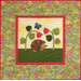 A quilt featuring a hedgehog walking among flowers and leaves, with a butterfly above.