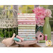 Stack of floral-patterned fat quarters beside pink flowers and a birdhouse display.