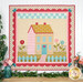 A colorful quilt depicting a colorful house with flowers, and a picket fence.