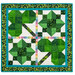 The completed Pieceful Patchwork - March wall hanging, a clover themed project colored in vibrant green, white, and rainbow fabrics, isolated on a white wall.