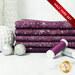 A stack of the six fabrics included in the 5 Half Yard Set Plum/Silver by Stof Fabrics with ornaments and thread.